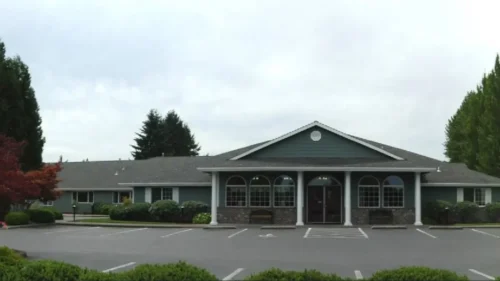 Bridge Creek building front view with large parking area and surrounding greenery